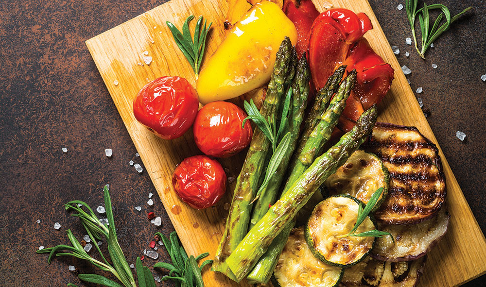 Grilled vegetables - zucchini, paprika, eggplant, asparagus and tomatoes served on wooden board - Quick Bites
